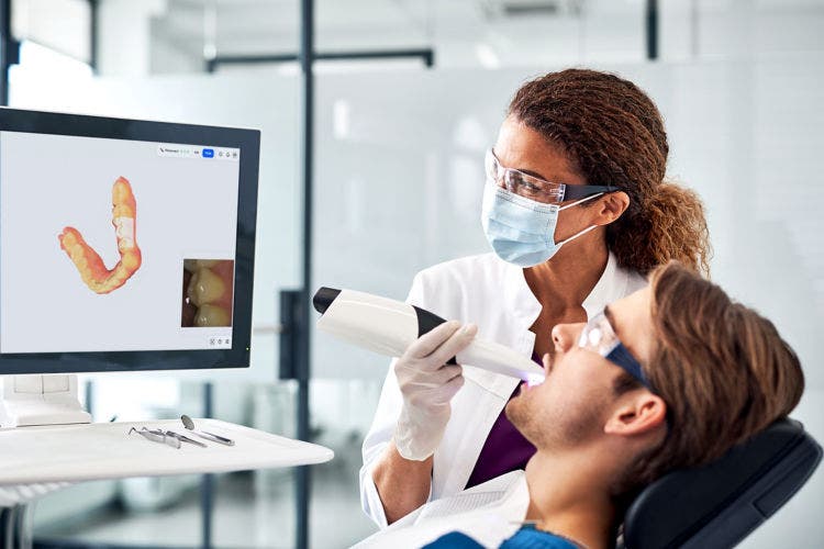 El clínico realiza un escaneo intraoral con Primescan 2 mientras el modelo digital aparece en la pantalla.
