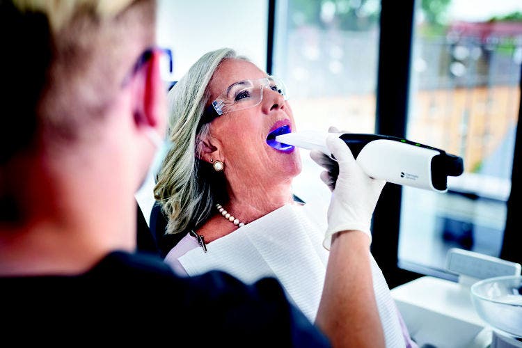 Odontólogo realizando un escaneo intraoral a un paciente utilizando un escáner de impresión digital.