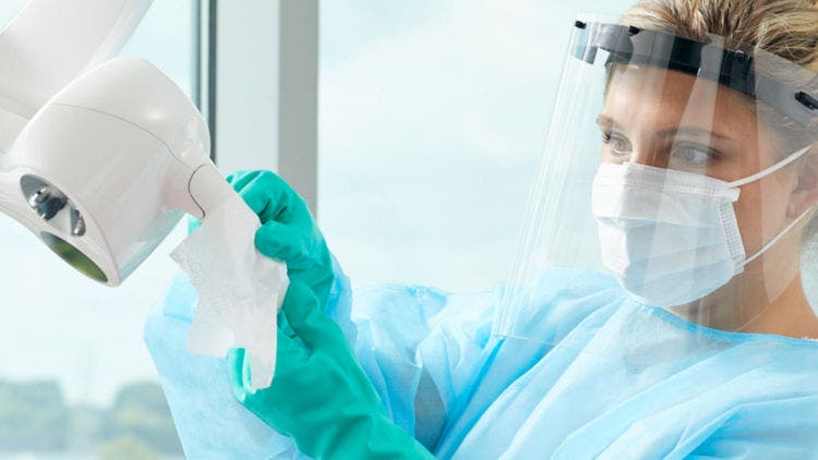 Dental professional preparing instruments and surfaces as part of infection prevention and clinical setup.