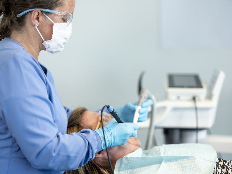 Procédure de détartrage par ultrasons effectuée pour éliminer le biofilm et le tartre lors des soins dentaires préventifs.
