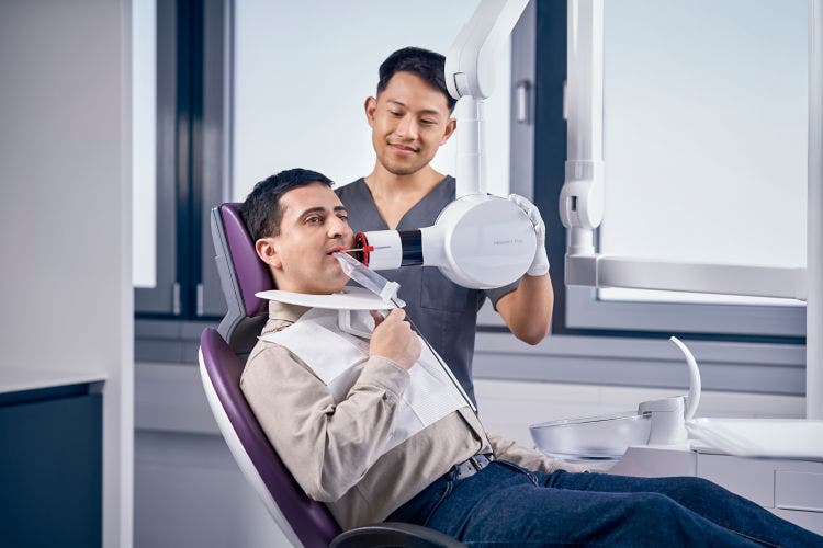 Un praticien réalise une radiographie dentaire intra-orale à l'aide d'un appareil d'imagerie portatif, tandis que le patient est positionné avec un bloc de morsure.