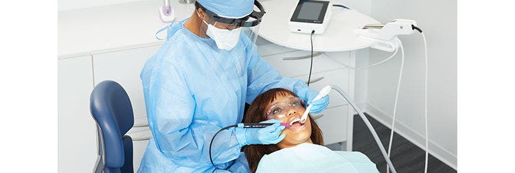 Un professionnel dentaire effectue un détartrage ultrasonique sur un patient dans un cabinet dentaire.